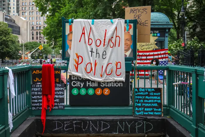 A subway entrance with Defund and Abolish the Police signs